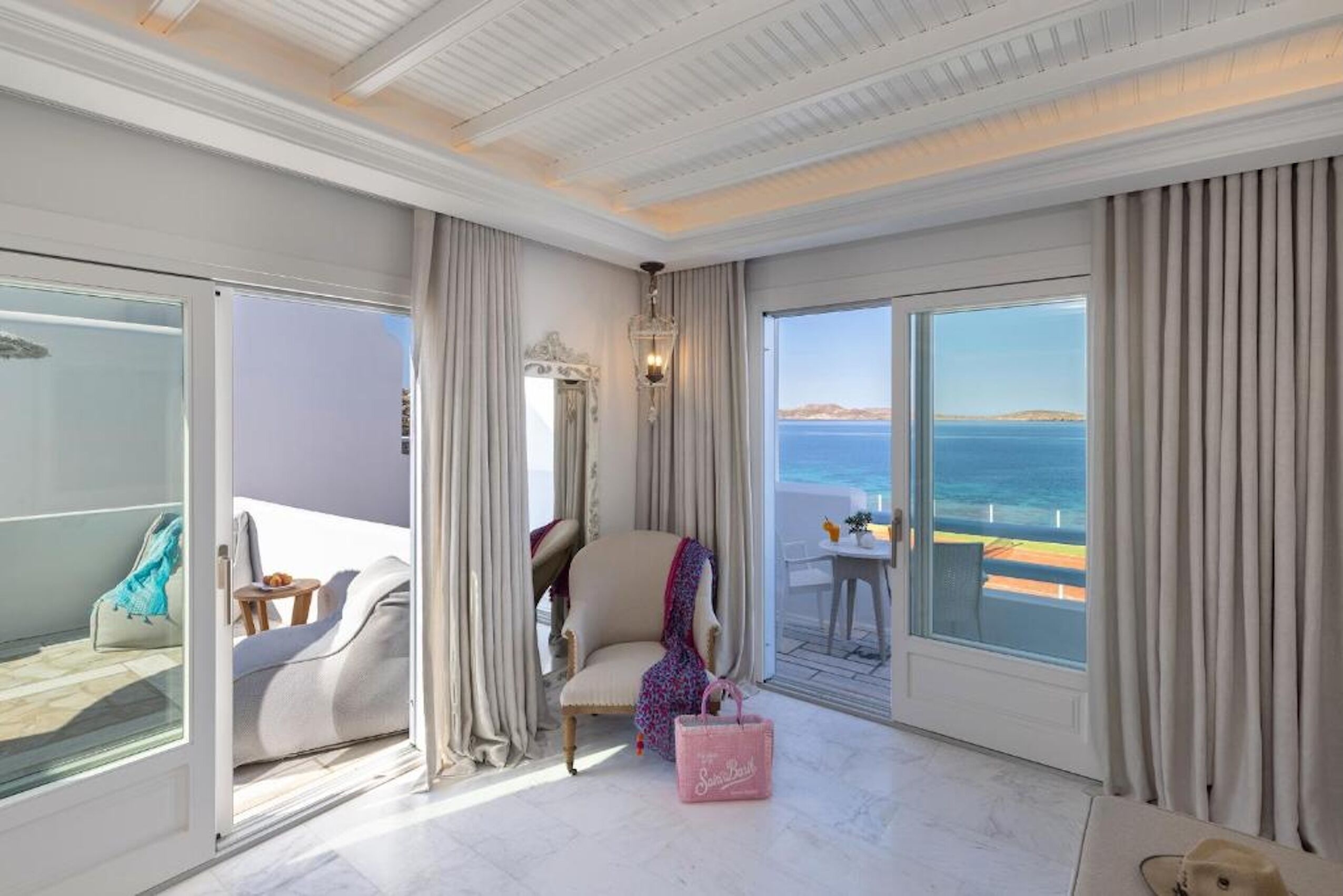 A spacious room with a large sliding glass door leading to a balcony with a view of the sea.