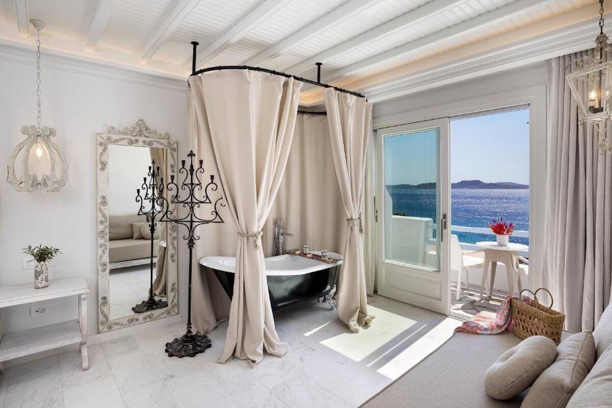 Une salle de bain luxueuse avec une baignoire îlot, un grand miroir et une vue sur la mer.