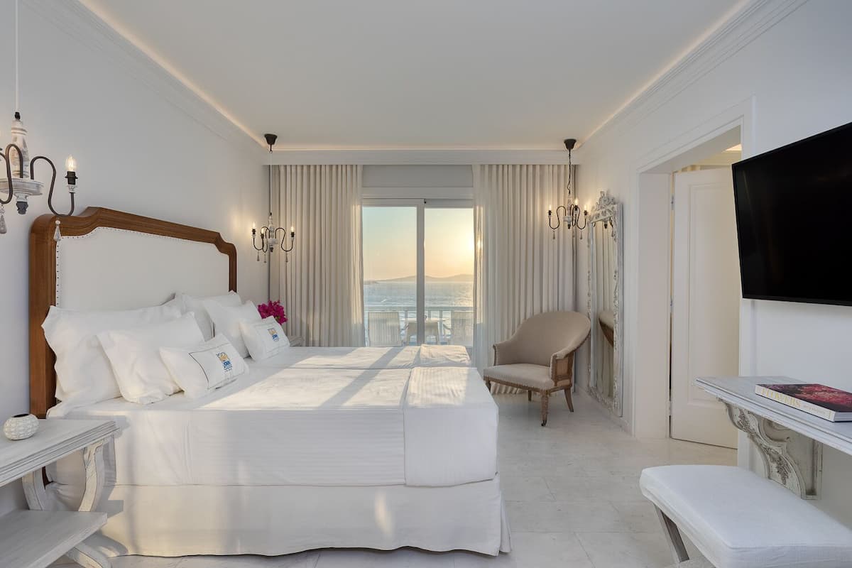 Une chambre d’hôtel avec un grand lit, une chaise, une télévision et une vue sur l’océan.