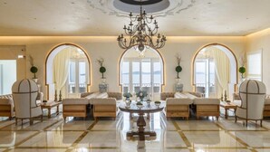 A spacious lobby with a polished marble floor, elegant sofas, and a grand chandelier.