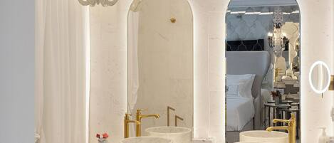 A modern bathroom with a large mirror, two sinks, and a chandelier.