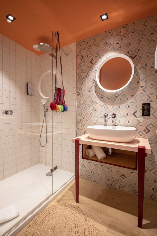 Une salle de bain moderne avec une douche à parois de verre, un meuble-lavabo avec un miroir et des carreaux muraux à motifs.