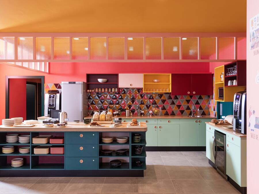 Een moderne keuken met een centraal eiland, inbouwapparatuur en een kleurrijke spatwand.