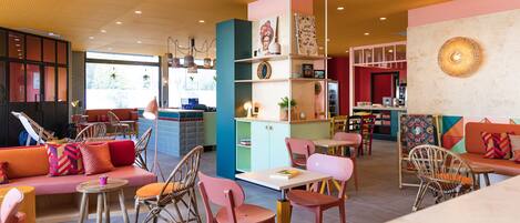 A modern interior with a mix of seating areas, including a sofa and chairs, and a dining area with tables and chairs.