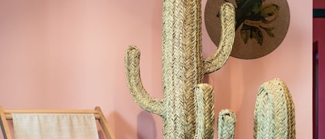 A room with a canvas painting on a easel, two large woven cacti sculptures, and two circular wall decorations.