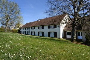 Uma casa de dois andares com telhado inclinado, paredes externas brancas e persianas pretas.