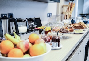 Um buffet de café da manhã com frutas, doces e acompanhamentos.