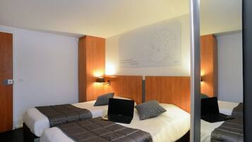Habitación de hotel con dos camas, cada una con una laptop y almohadas. Hay una obra de arte colgada en la pared sobre las camas.