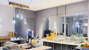 Een moderne ontbijtruimte met een buffet, inclusief diverse etenswaren en drankjes.