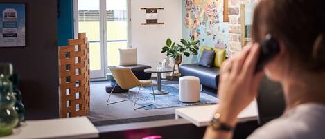 A modern office space with a desk, chair, and a seating area with a sofa and a coffee table. There are decorative plants and a wall with a map.