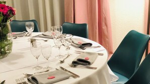 A round dining table with a white tablecloth, set with cutlery, glasses, and folded napkins. - Hotel La Maison de Lise Mulhouse Illzach (Illzach)