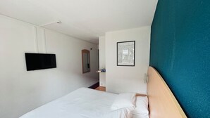 A hotel room with a bed, a television mounted on the wall, a framed map, and a wooden headboard. - Hotel La Maison de Lise Mulhouse Illzach (Illzach)