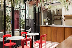 A restaurant interior with red chairs, a checkered floor, and hanging plants. - Hôtel Dalila (Paris)