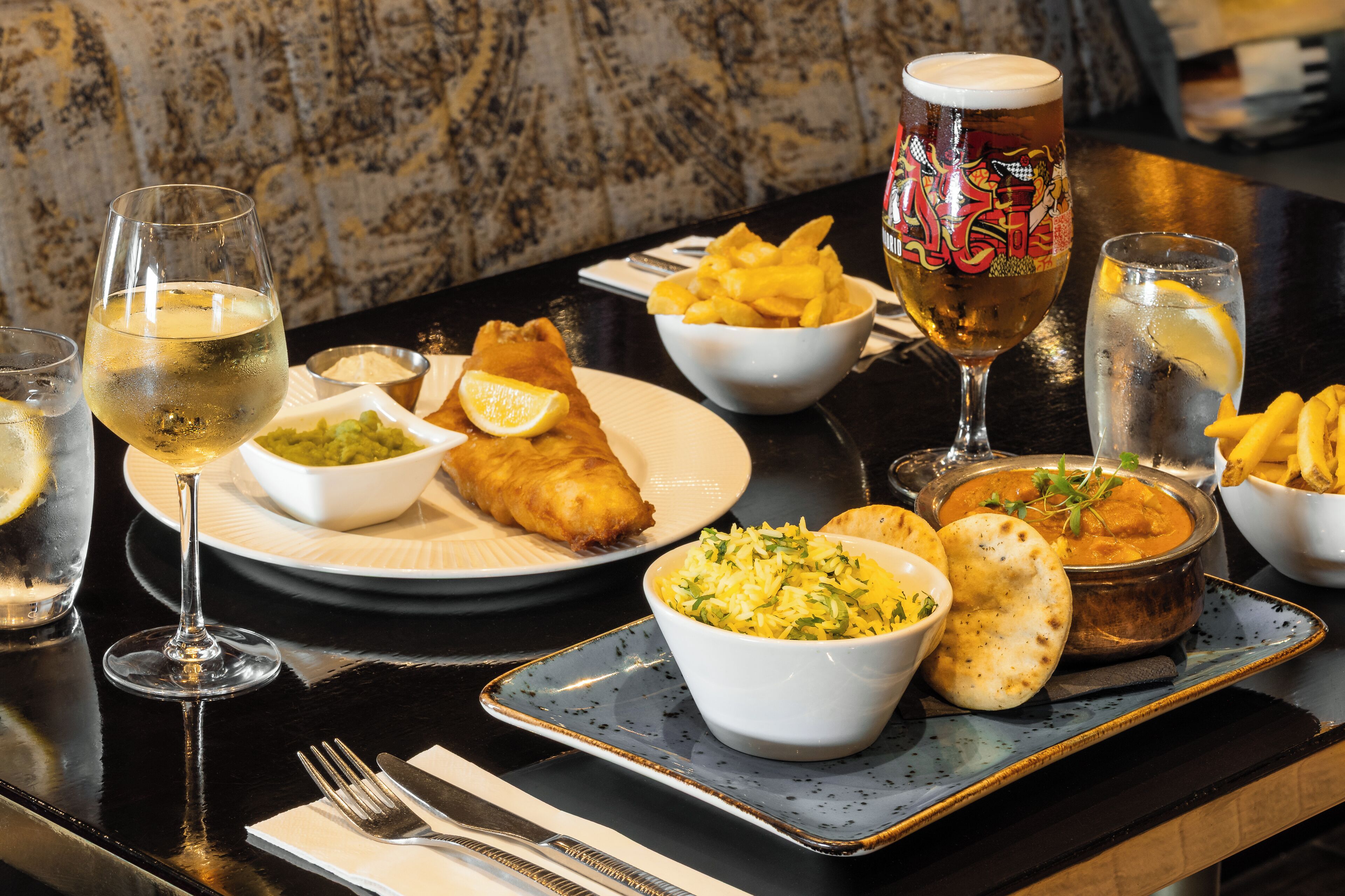 Una mesa con comida y bebidas, incluyendo pescado, arroz y cerveza.