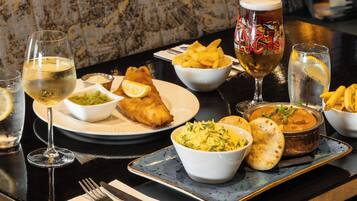Una mesa con comida y bebidas, incluyendo pescado, arroz y cerveza.