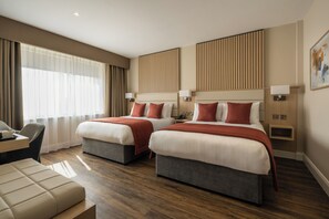 A hotel room with two beds, a desk, and a chair.