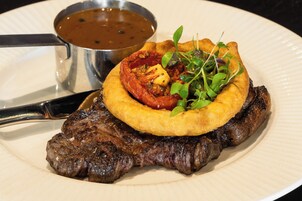 Un filete con una hamburguesa frita y salsa sobre un plato.