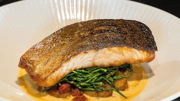 A plate with a piece of fish, green beans, and a creamy sauce.