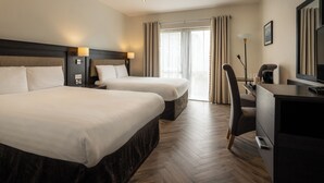 A hotel room with two beds, a desk, a chair, a television, and a large window with curtains. - Da Vinci's Hotel Derry (Londonderry)