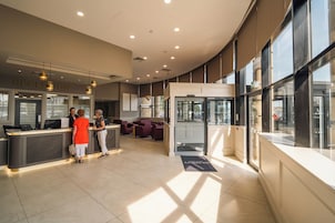 Zona de recepción de hotel con mostrador, asientos y amplias ventanas.