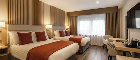 A hotel room with two beds, a desk, and a chair.