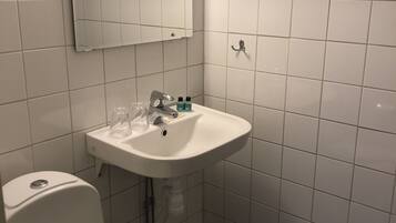 Un baño con un lavamanos blanco, un espejo y dos toalleros.