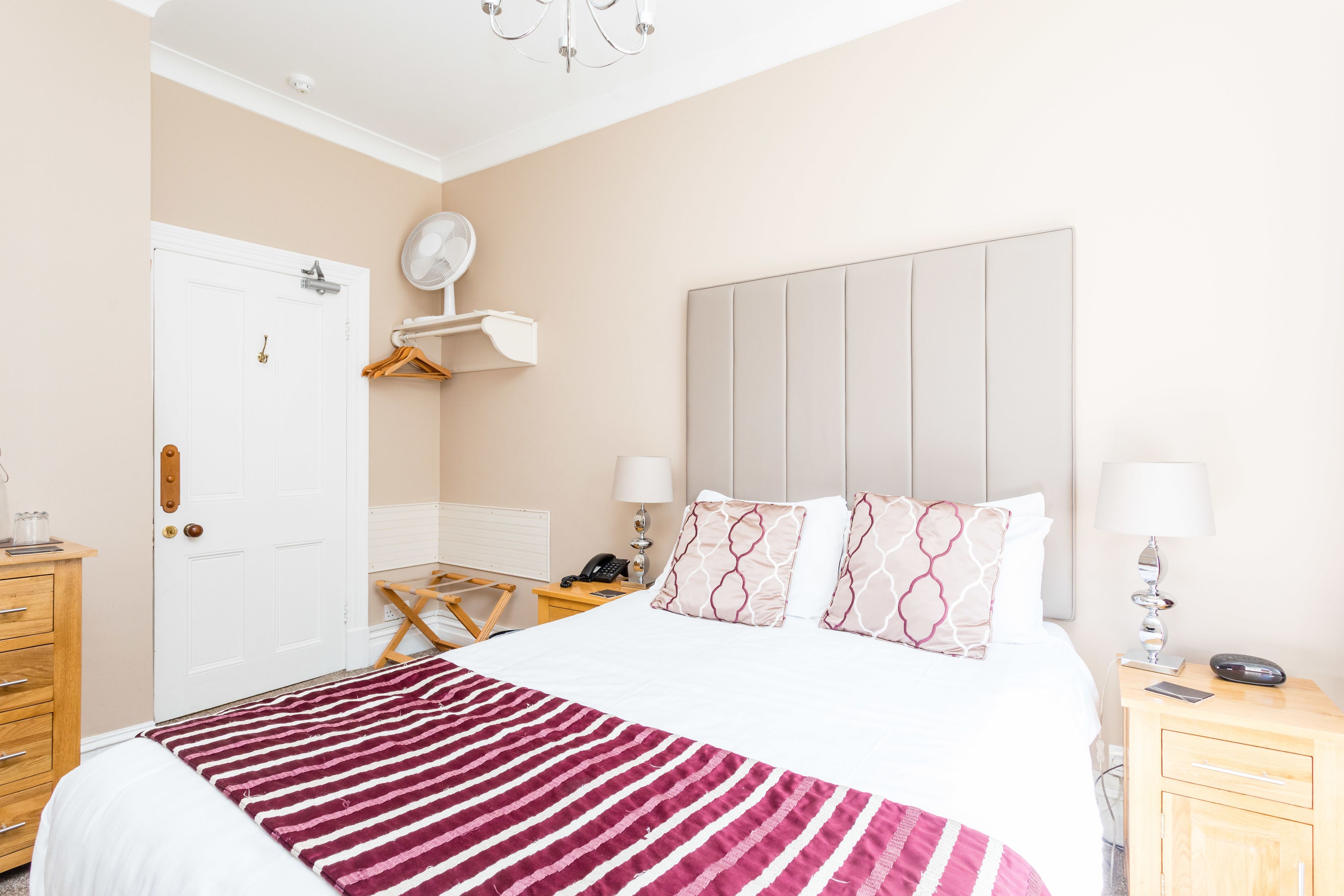 Habitación de hotel con cama, mesitas de noche, escritorio, silla, armario y puerta.