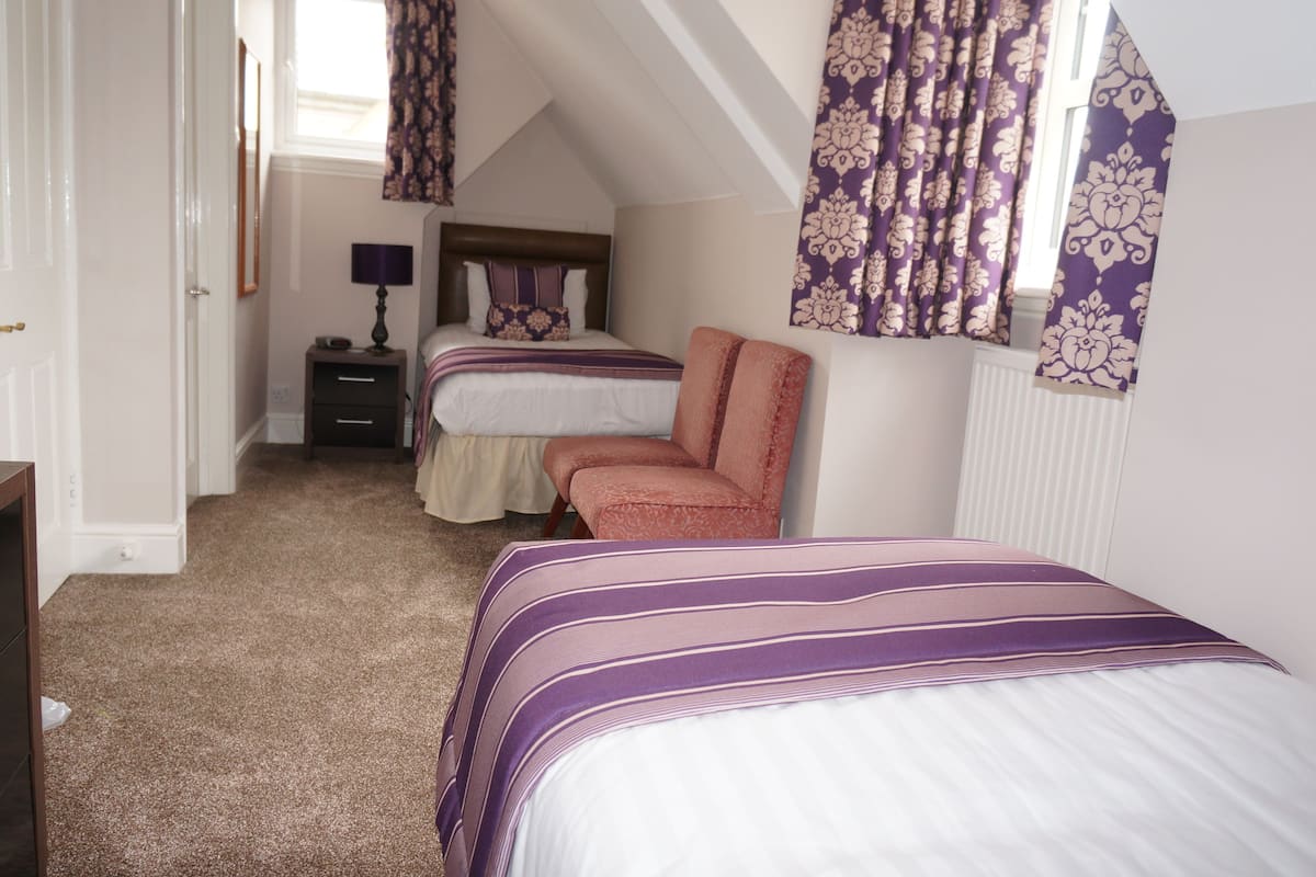 A bedroom with two beds, a nightstand, and a chair.