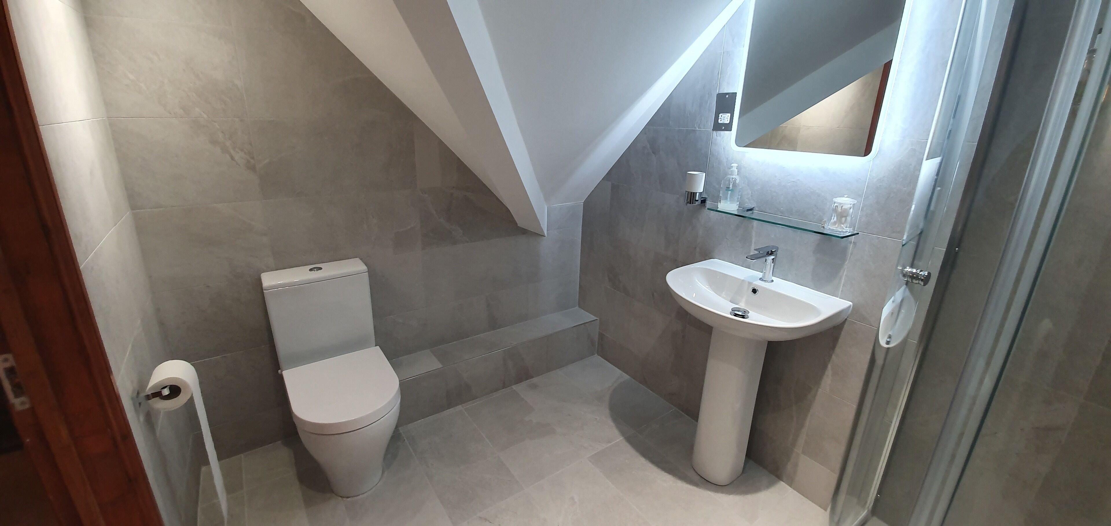 Une salle de bain moderne équipée de toilettes, d’un lavabo et d’une douche à parois en verre.