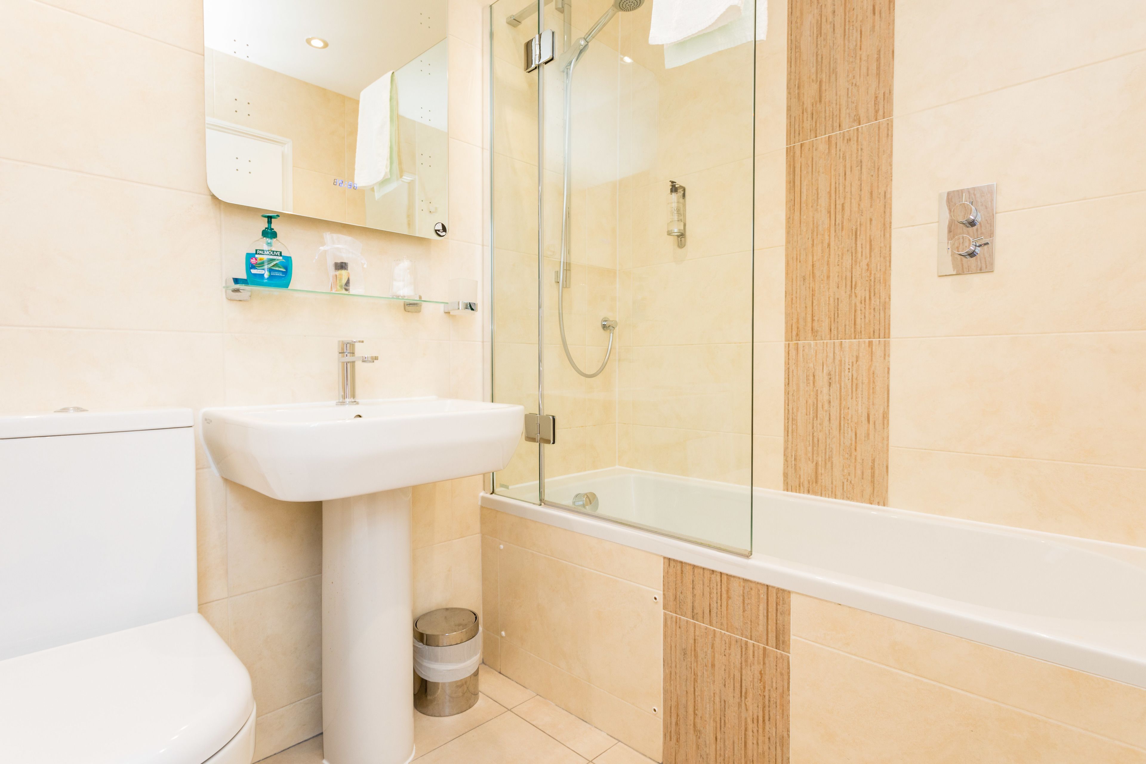 A modern bathroom with a glass-enclosed shower, a white sink, and a toilet.