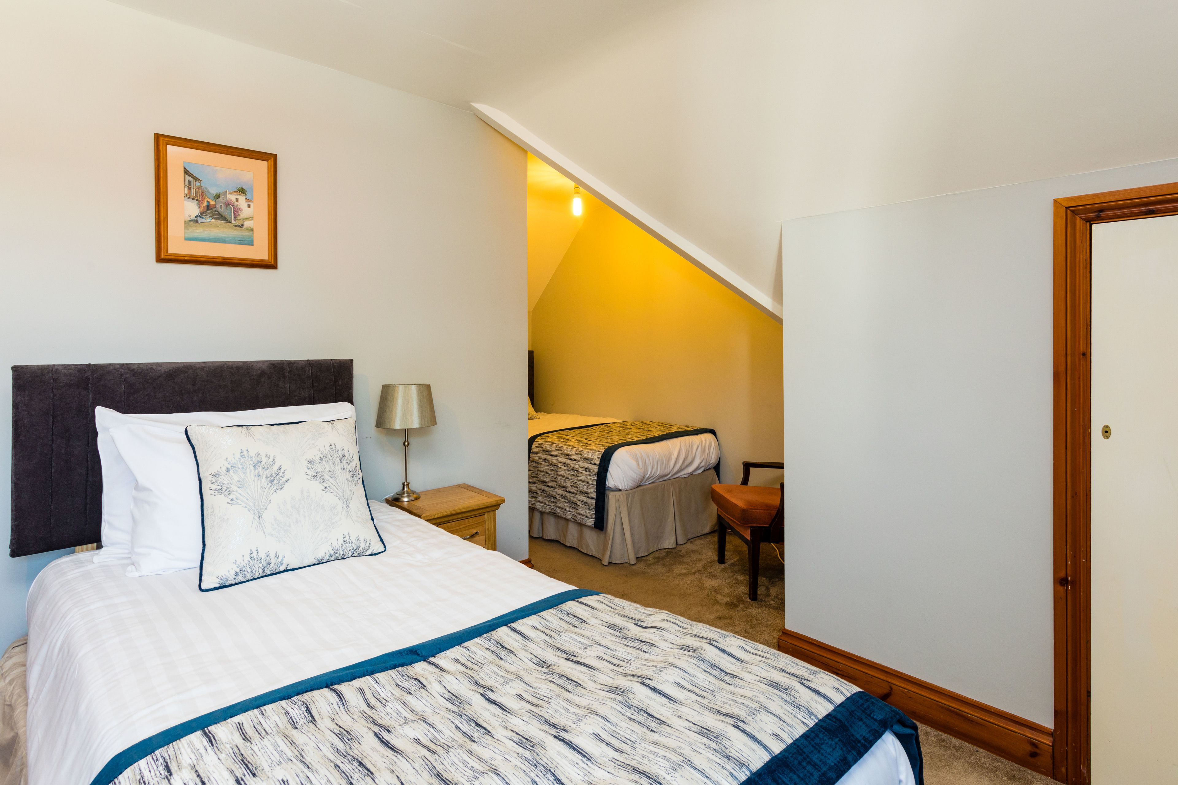 A bedroom with a large bed, a smaller bed, a desk, and a chair.