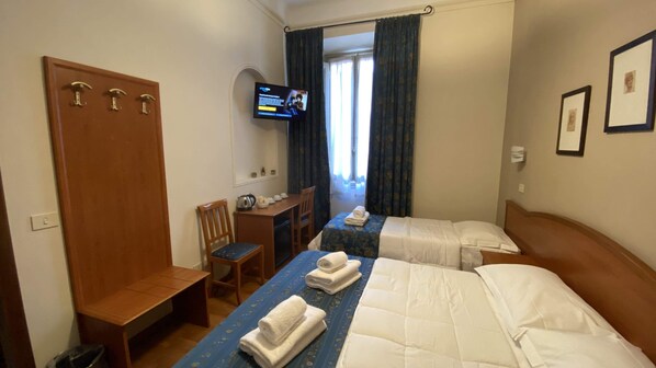 A hotel room with two beds, a desk, a chair, a TV, and a wardrobe.