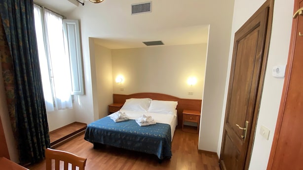 Ein Hotelzimmer mit einem Bett, Nachttischen, einem Schreibtisch und einem Sessel.