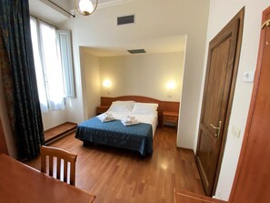 A hotel room with a bed, bedside tables, a desk, and a chair.