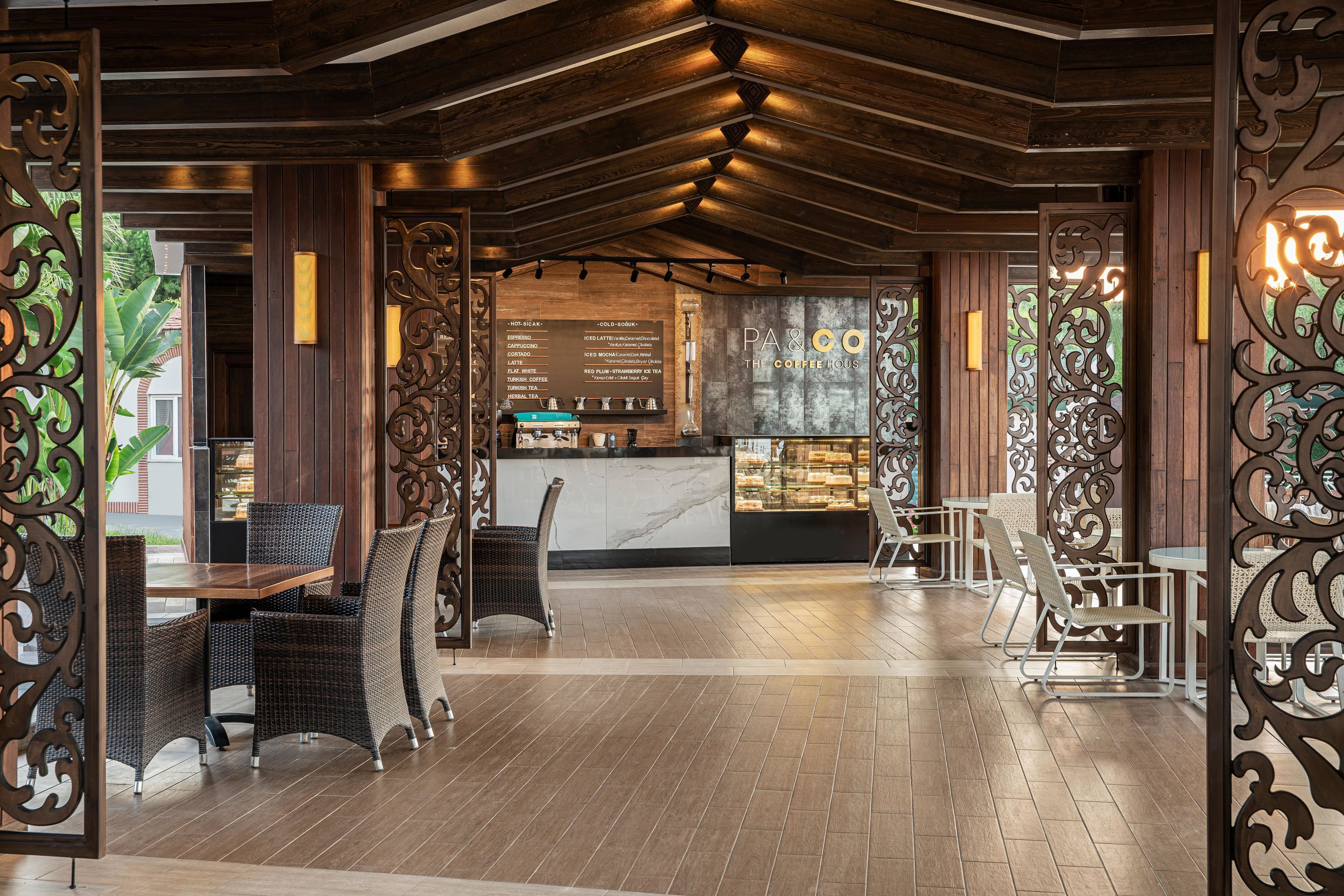 L’intérieur d’un café moderne se caractérise par un lambris en bois, des meubles en osier et un tableau des prix bien visible.