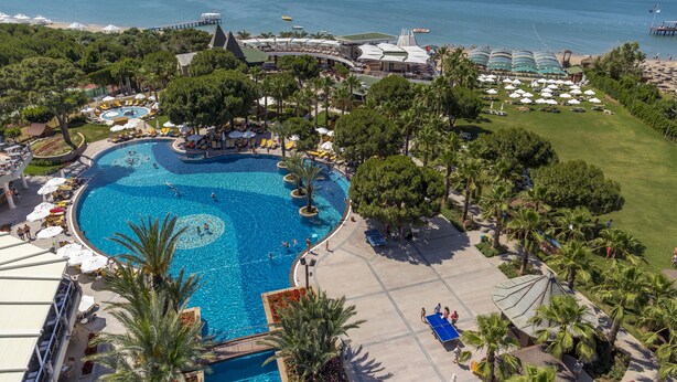 Un resort con una grande piscina centrale, diverse aree spiaggia e un molo che si protende verso il mare.