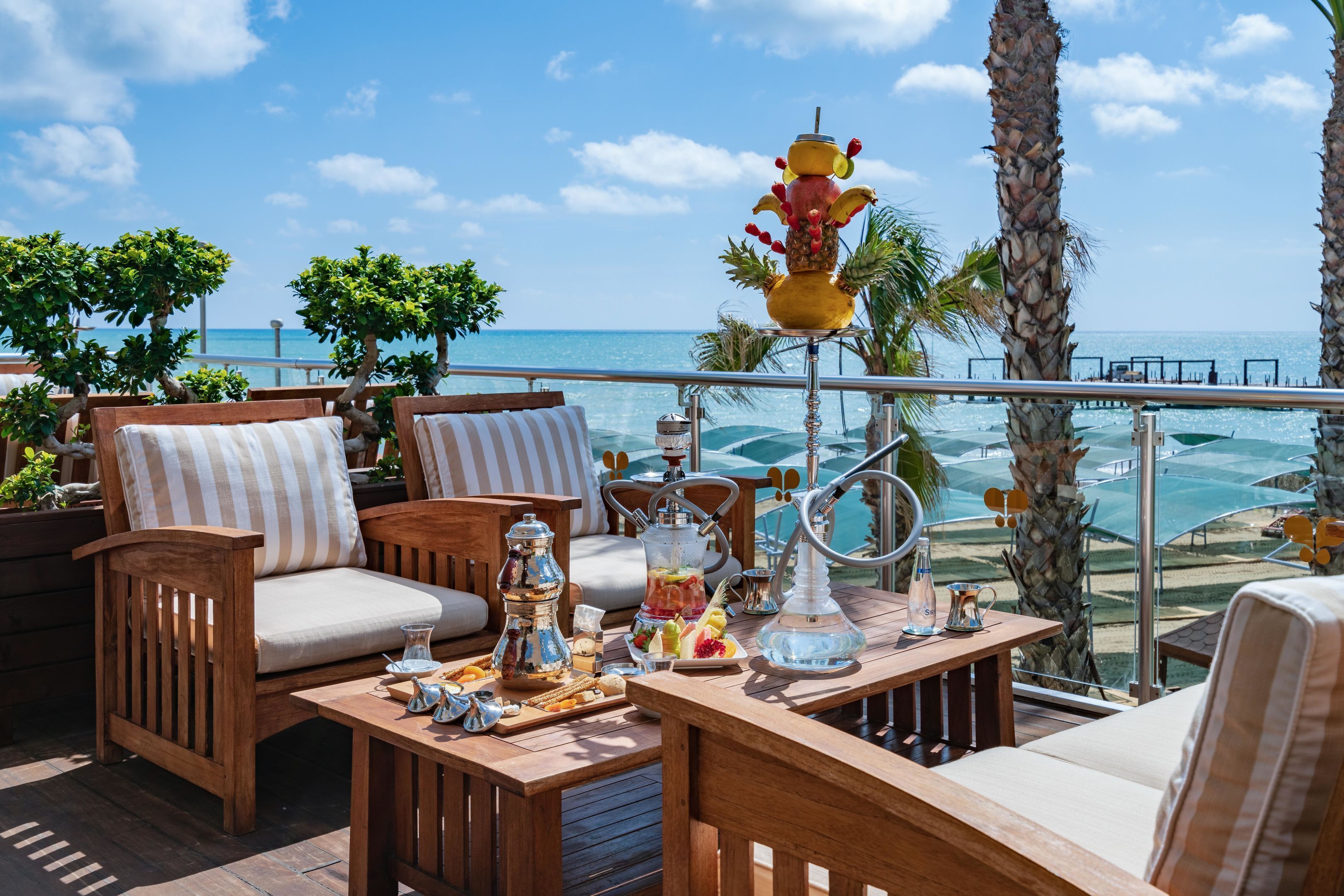 A wooden deck with outdoor furniture, a fruit sculpture, and a view of the ocean.