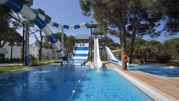 Enjoy thrilling water slides and a refreshing pool surrounded by lush trees and a wooden deck.