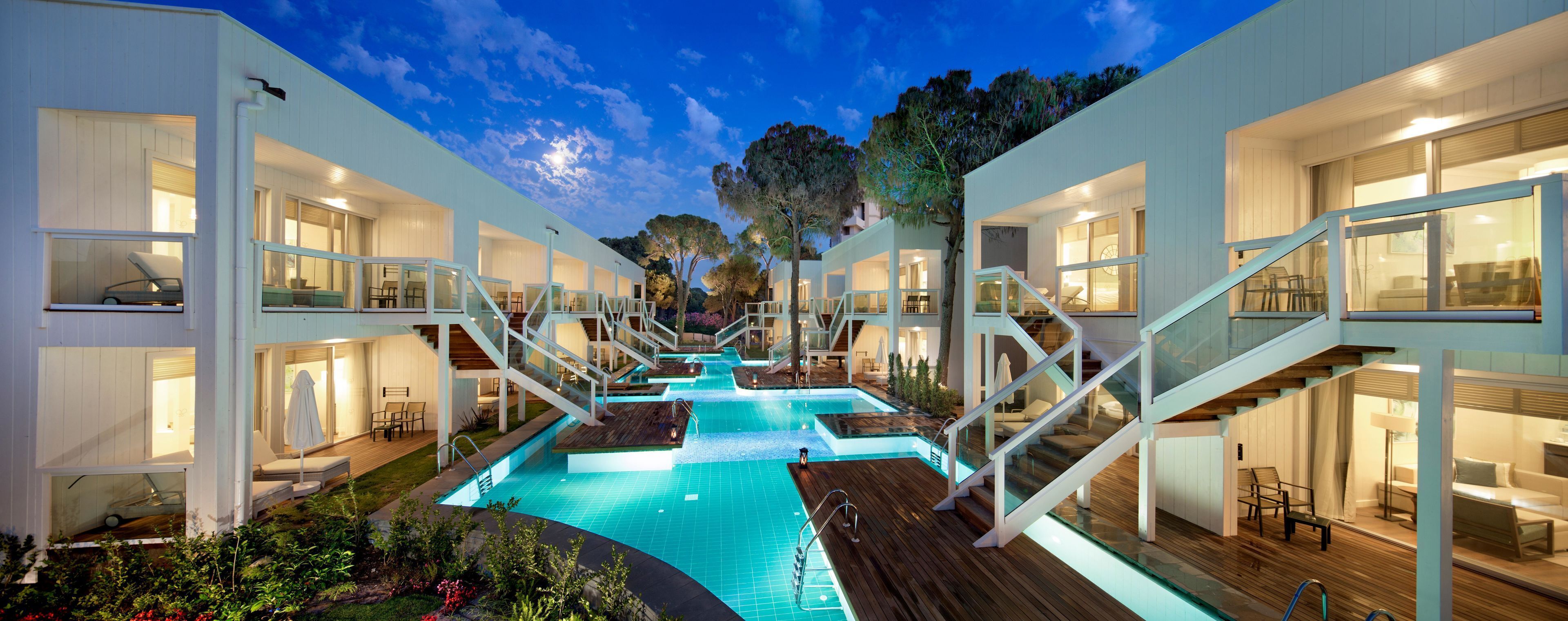 Un hôtel moderne doté d’une piscine centrale, de nombreux balcons et d’un escalier reliant les différents étages.