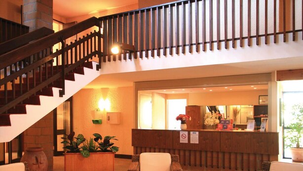 A lobby with wicker furniture, a reception desk, and a staircase. - Résidence Lagrange Vacances du Golf (Saint-Cyprien)
