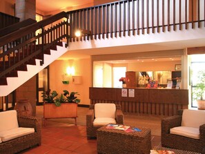 A lobby with wicker furniture, a reception desk, and a staircase. - Résidence Lagrange Vacances du Golf (Saint-Cyprien)