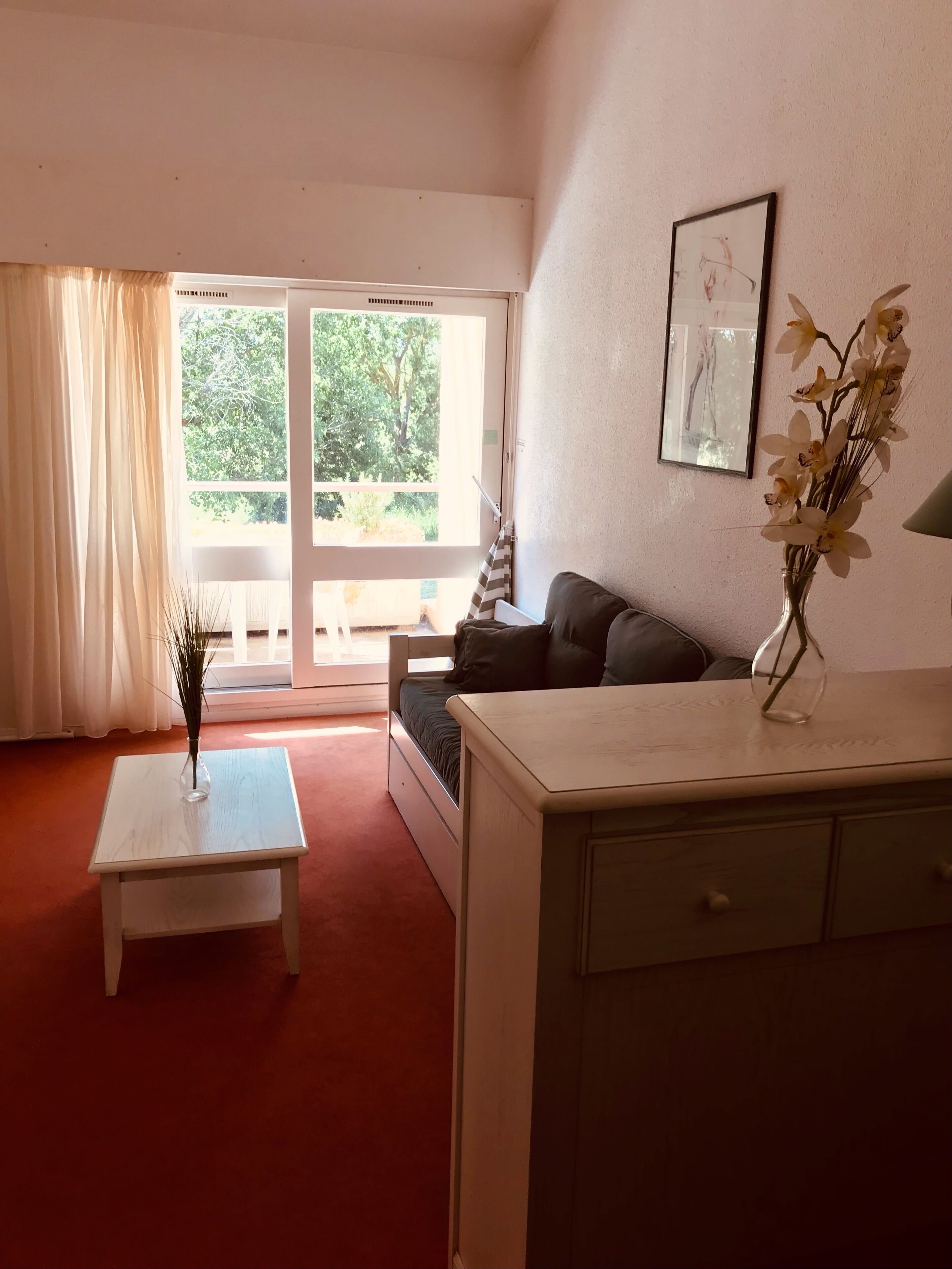 Une pièce comprenant un lit, une petite table avec un vase, un canapé et un meuble.