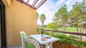 A balcony with a white table and chairs, a bottle, and a plate of food. - Résidence Lagrange Vacances du Golf (Saint-Cyprien)
