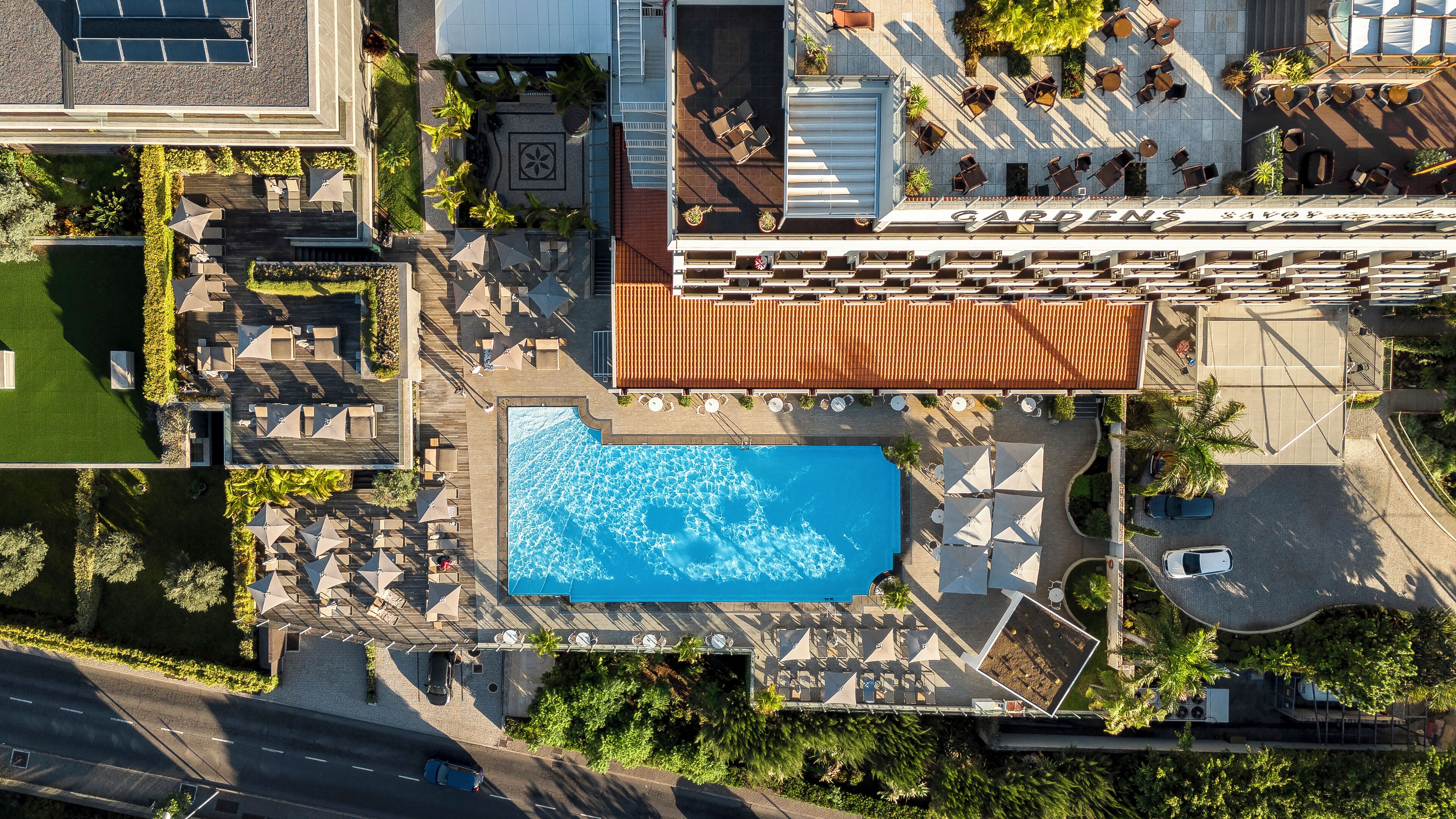 Vista aérea de un hotel con piscina, mobiliario exterior y jardín.