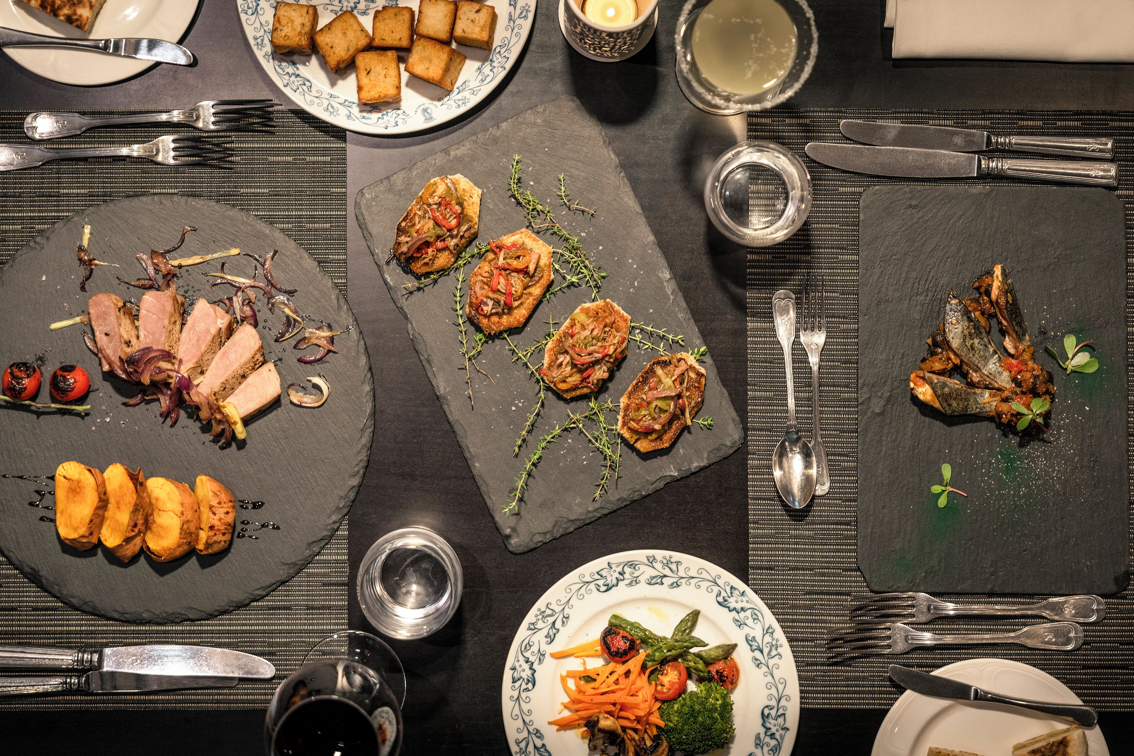 A dining table set with plates of food, cutlery, and glasses.