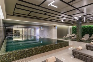 Una piscina cubierta, una piscina al aire libre, sombrillas, tumbonas