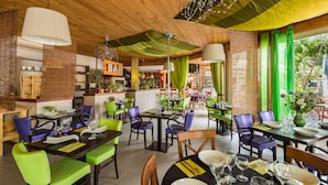 A restaurant with wooden ceiling, green and purple chairs, and a bar area.
