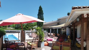 A covered outdoor area with a pool, wooden deck, and outdoor seating.
