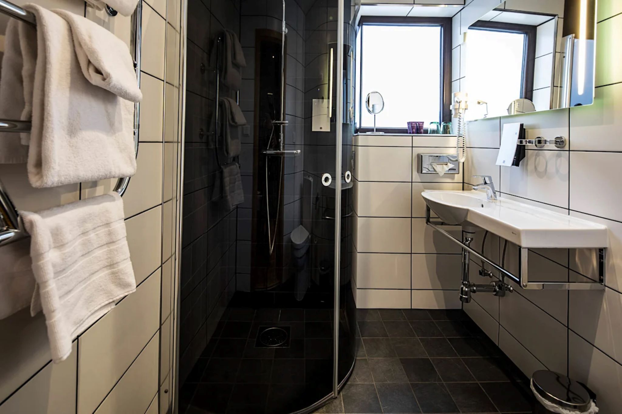 Een moderne badkamer met een douchecabine van glas, een wit wastafelmeubel en een spiegel erboven.
