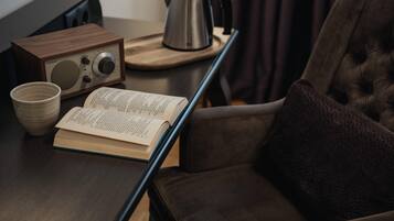 A wooden table with a radio, a kettle, a book, and a cup.